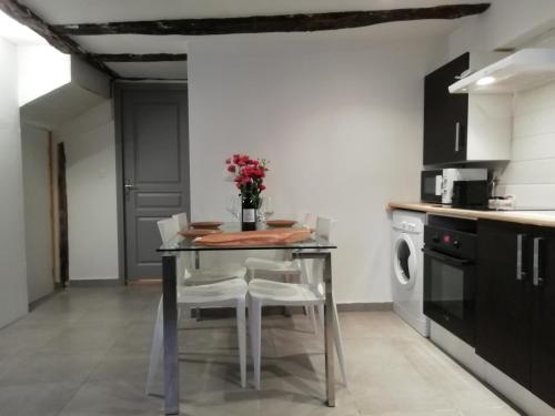 a kitchen with a table and chairs with a vase of flowers at L'éden Quercynois in Souillac