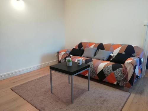 a couch with pillows and a table in a living room at L'éden Quercynois in Souillac