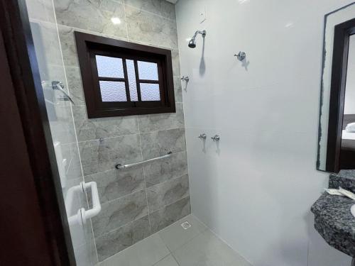 a bathroom with a shower with a glass door at Pousada Battistella in Garopaba