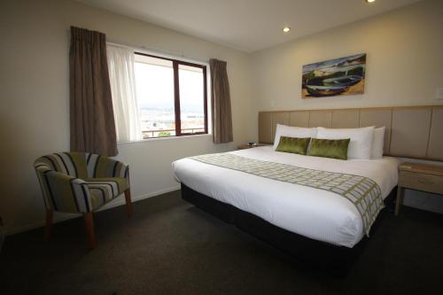 a hotel room with a bed and a chair and a window at 555 Motel Dunedin in Dunedin
