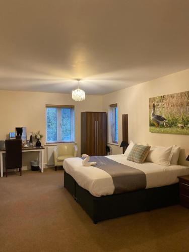 a bedroom with a large bed with a desk and a computer at Woodhouse Farm Lodge in Spalding