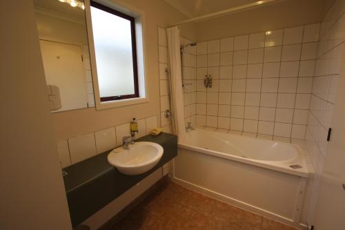 a bathroom with a sink and a bath tub at 555 Motel Dunedin in Dunedin