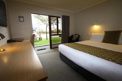 Habitación de hotel con cama y puerta corredera de cristal en 555 Motel Dunedin en Dunedin