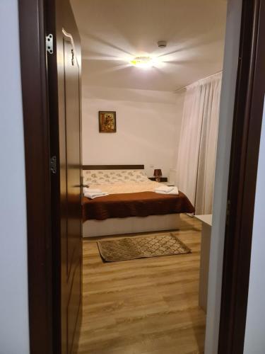a bedroom with a bed and a door leading into a room at Candy Pensiune&Restaurant in Dumbrava Roşie