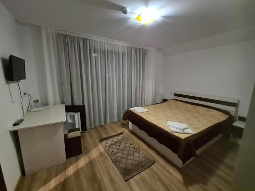 ein Schlafzimmer mit Bett, Schreibtisch und Fernseher in der Unterkunft Candy Pensiune&Restaurant in Dumbrava Roşie