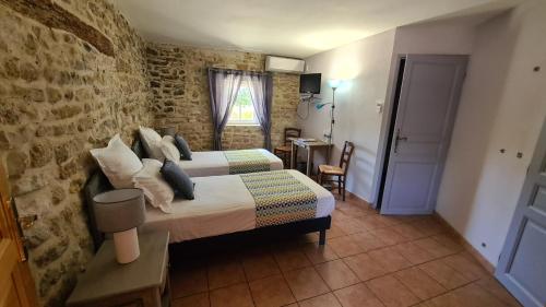1 dormitorio con cama y pared de ladrillo en La Bastide Saint Bach en Suze-la-Rousse