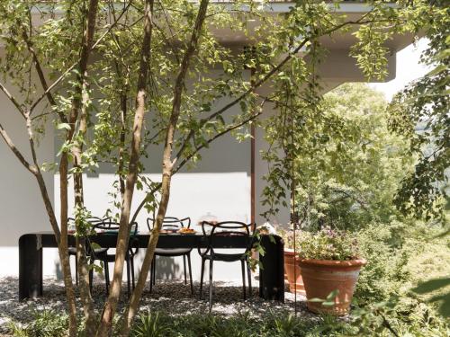 a table and chairs in a patio with trees at LARIUM BED & BREAKFAST - PIGRA in Pigra