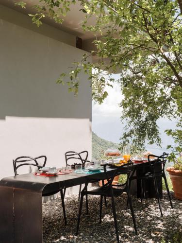 a table and chairs with a table and a tree at LARIUM BED & BREAKFAST - PIGRA in Pigra
