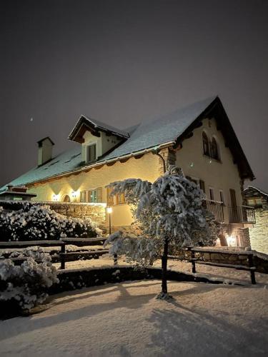 a snow covered house with a tree in front of it at Casa Brencio in Masera