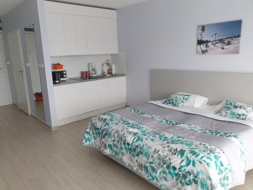 a white bedroom with a bed and a kitchen at Apartament Czarna Góra Faktura VAT in Sienna