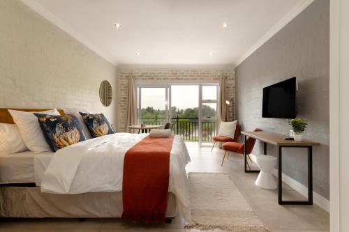a bedroom with a bed and a desk and a television at Alimama Spaces The Chelsea's Cote de Val studio in Parys