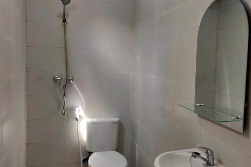 een badkamer met een toilet, een wastafel en een spiegel bij KoolKost near Millennium ICT Center Medan (Minimum Stay 6 Nights) in Pulauberayan