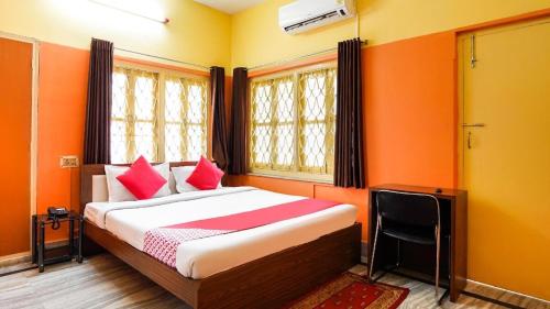 um quarto com paredes laranja e uma cama com almofadas vermelhas em Hotel Galaxy Inn em Calcutá