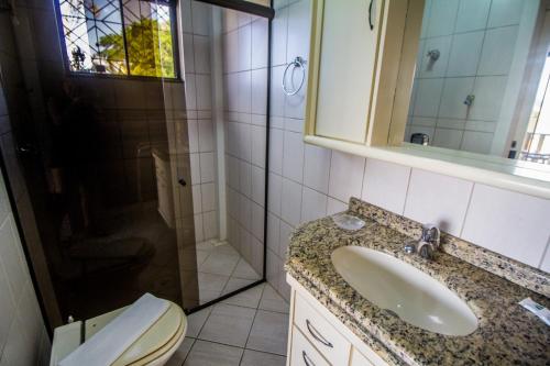 a bathroom with a sink and a toilet and a mirror at Pousada Al Mare in Bombinhas