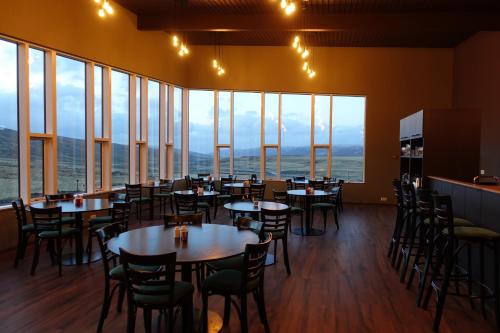 Un comedor con mesas y sillas y grandes ventanales. en Basalt Hotel, en Iðunnarstaðir