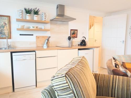 a kitchen with white cabinets and a couch in a room at Beachfront Studio Apartment in Felixstowe