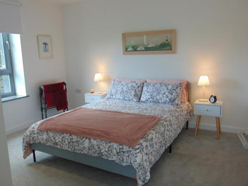 a bedroom with a bed with two tables and two lamps at Driftwood, Donaghadee in Donaghadee