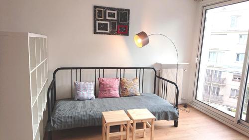 a bedroom with a bed with pillows and a lamp at Renovated, 37m², 2 min walk Tram, 5 min La Défense in La Garenne-Colombes