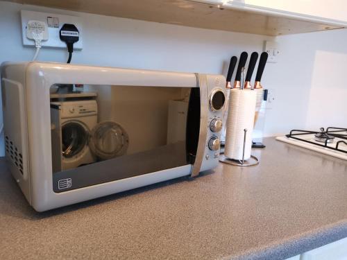 a microwave sitting on a kitchen counter with knives at Welcome to St Helena Dunoon, a traditional villa in Dunoon