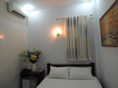 a bedroom with a bed and a window with a plant at Vy Khanh Guesthouse in Ho Chi Minh City