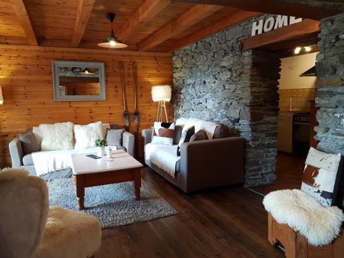 a living room with two couches and a stone wall at Chalet d'Heïdi in Bourg-Saint-Maurice