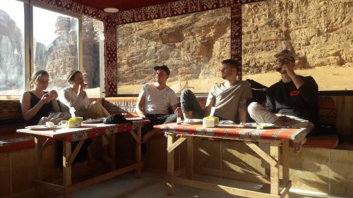 un groupe de personnes assises sur des tables dans une pièce dans l'établissement Salman Zwaidh Camp, à Wadi Rum