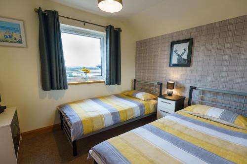 Un dormitorio con dos camas y una ventana. en Lossiemouth Haven, en Lossiemouth