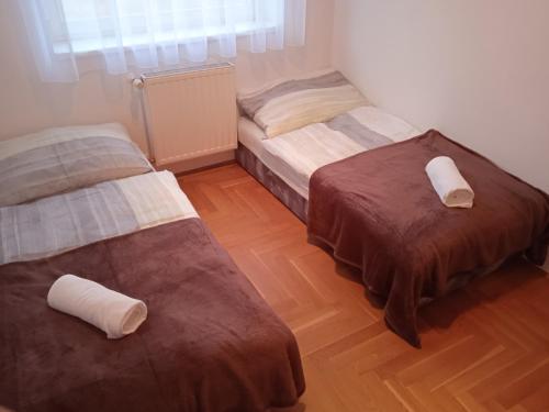 two beds in a room with wooden floors at Family apartment-családias hangulat in Győr