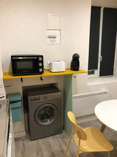 eine Küche mit einer Waschmaschine und einer Mikrowelle in der Unterkunft Chez Julien: appartement confort plein centre in Lunéville