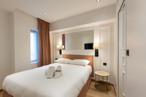 Cette chambre comprend un grand lit blanc et un miroir. dans l'établissement HOTEL AU COEUR DE REPUBLIQUE, à Paris