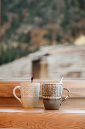 two coffee cups sitting on a window sill at Pimont Alpine Chalet in Madonna di Campiglio