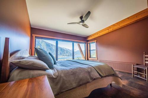 a bedroom with a large bed with a large window at Luxe Modern Timberframe - Iconic Panorama Views with AC in Nelson