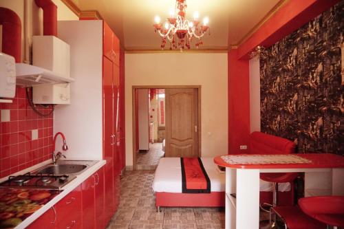 eine Küche mit roten Schränken, einem Tisch und einem Waschbecken in der Unterkunft Doba In Ua Yavornytskoho119 Apartments in Dnipro