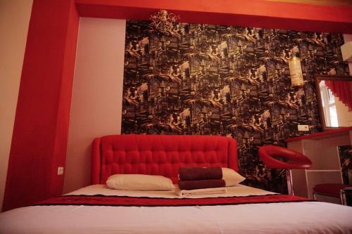 Bett mit rotem Kopfteil in einem Zimmer in der Unterkunft Doba In Ua Yavornytskoho119 Apartments in Dnipro