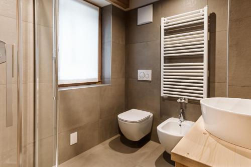 a bathroom with a toilet and a sink and a window at Pimont Alpine Chalet in Madonna di Campiglio