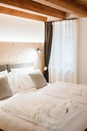 two white beds in a room with a window at Pimont Alpine Chalet in Madonna di Campiglio