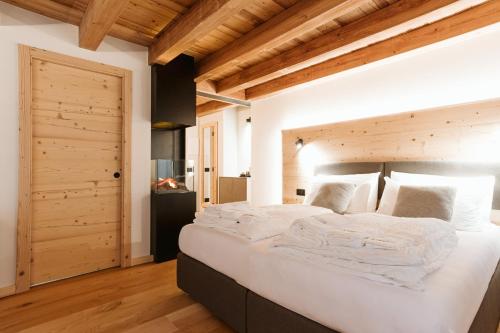 a bedroom with a large white bed with wooden ceilings at Pimont Alpine Chalet in Madonna di Campiglio