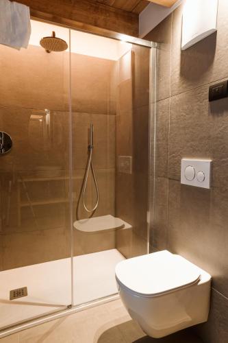 a bathroom with a shower with a toilet and a glass shower door at Pimont Alpine Chalet in Madonna di Campiglio