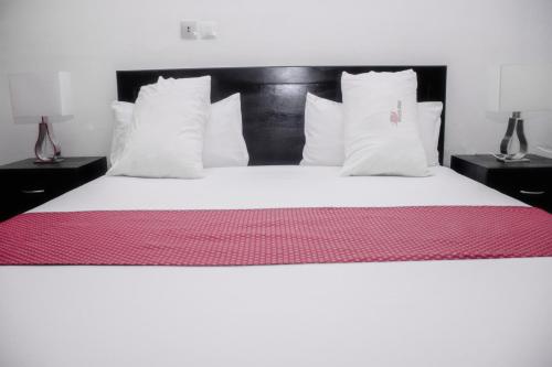 a large bed with white sheets and pillows at Hotel Djigui in Abidjan