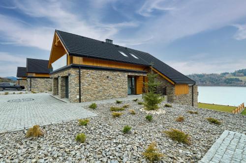 a stone house with a black roof and a driveway at Apartamenty nad jeziorem, Czorsztyn - Kluszkowce in Czorsztyn