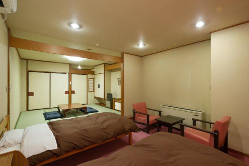 una camera con due letti e un tavolo con sedie di kinugawaonsen Fukumatsu a Nikko