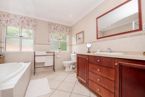 a bathroom with a tub and a sink and a toilet at Wild Olive Executive Suite in Johannesburg