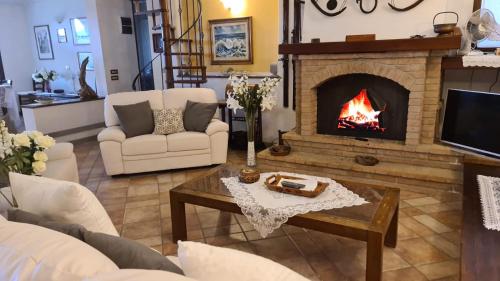 a living room with a fireplace and white furniture at Villa Le Agavi & Spa in Scarlino