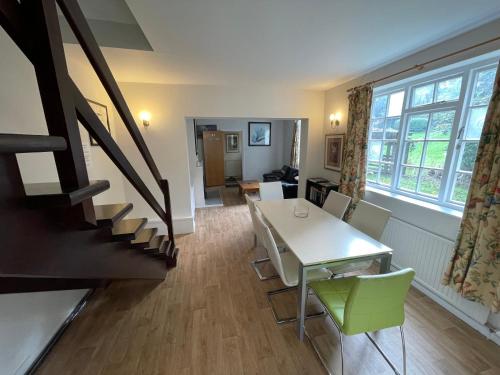 a living room with a table and chairs and a staircase at Garden House in Nailsworth