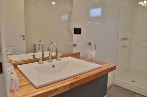 Un baño con lavabo blanco y ducha en Espino Blanco Apartamentos, en San Carlos de Bariloche