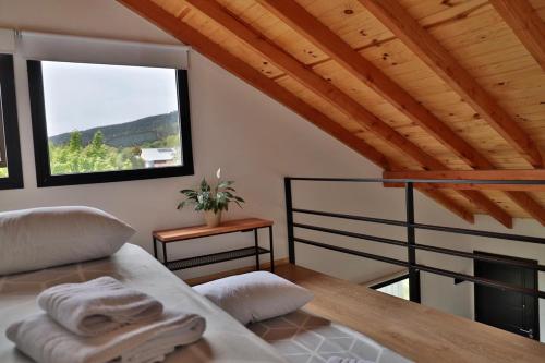 Un dormitorio con una cama y una ventana grande en Espino Blanco Apartamentos, en San Carlos de Bariloche