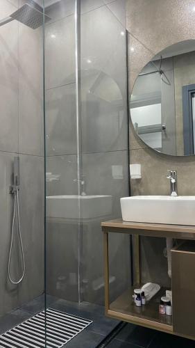 a bathroom with a shower and a sink and a mirror at Bujtina Xhabakja in Belsh-Qendra