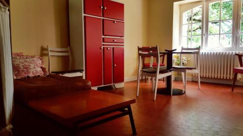 a living room with red cabinets and a table and a couch at Gîte rural - La Rivière Assoiffée in Florimont-Gaumiers