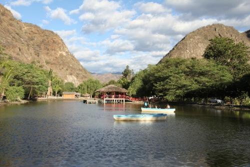two boats in a lake with a gazebo and mountains at Hotel Dubái in Catamayo