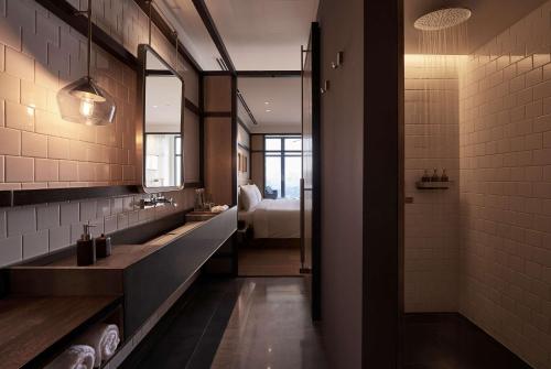 - une salle de bains avec deux lavabos et un lit dans une chambre dans l'établissement Alila Bangsar Kuala Lumpur, à Kuala Lumpur